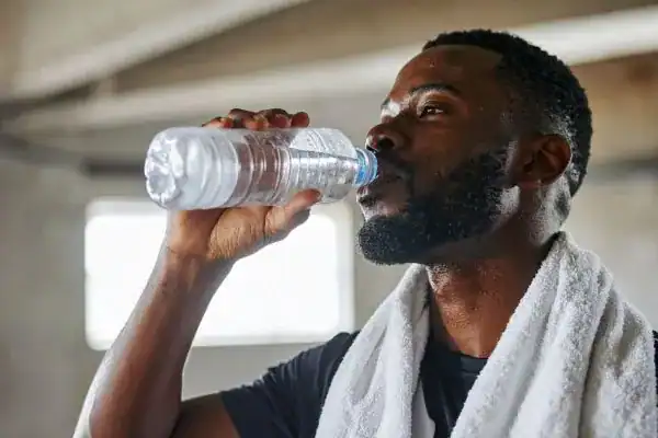 Image of man drinking water to improve hydration Melton Mowbray after work out.